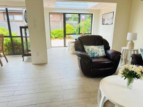 a living room with a leather chair and a table at A Home Away from Home - Bucklands Beach Luxury 3-Bedroom Garden Villa in Auckland