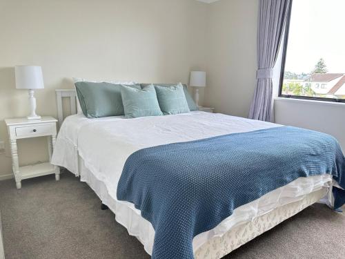 a bedroom with a bed with a blue and white blanket at A Home Away from Home - Bucklands Beach Luxury 3-Bedroom Garden Villa in Auckland