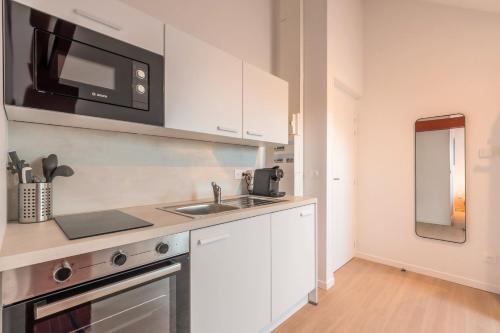 une cuisine avec un évier et un micro-ondes dans l'établissement Studio sous les combles côté rue, parking gratuit, à Villeneuve d'Ascq