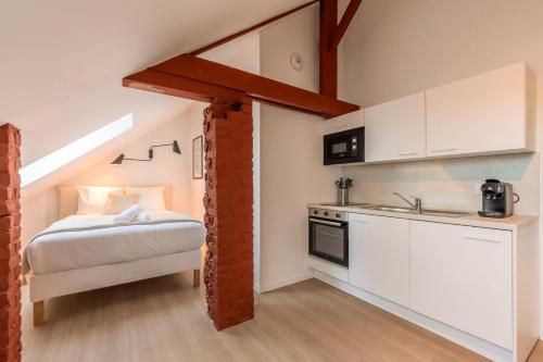 une cuisine avec des armoires blanches et un lit dans une chambre dans l'établissement Studio sous les combles côté rue, parking gratuit, à Villeneuve d'Ascq