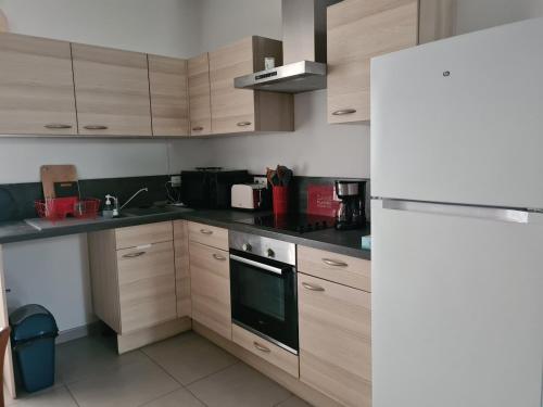 une cuisine avec des armoires en bois et un four à plaques de cuisson dans l'établissement Gîte de la Source, à Feuchy