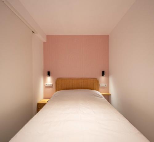 a bed in a small room with two lights on the wall at Apartamentos Turísticos de Soria Centro NF in Soria