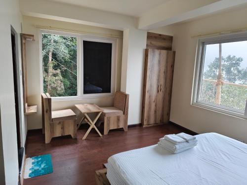 a bedroom with a bed and a chair and a window at Lamahatta Clouds Hotel & Restaurant in Takdāh