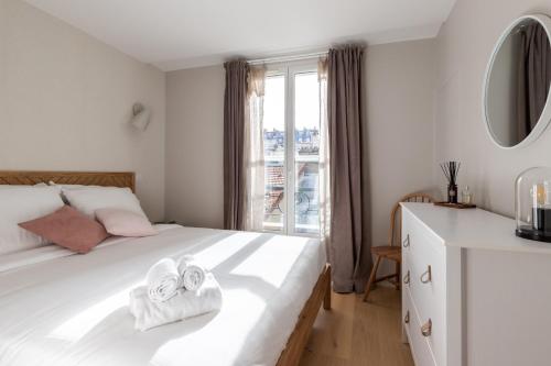 une chambre avec un lit blanc avec des serviettes dessus dans l'établissement Take It Easy in This Stylish Architect Flat, à Paris