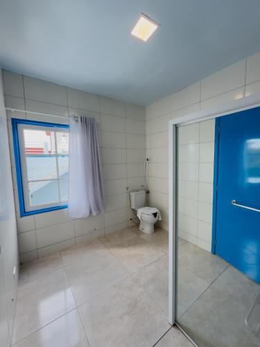 a bathroom with a toilet and a blue door at Hotel Paraiso Maragogi LTDA in Maragogi