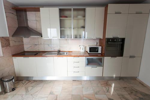 a kitchen with white cabinets and a sink at Apartmani Dajana in Primošten