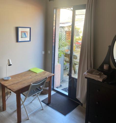 Cette chambre dispose d'une table en bois et d'une porte coulissante en verre. dans l'établissement CALME , PROCHE du Centre, Grande Terrasse, Petit déjeuner, à Bordeaux