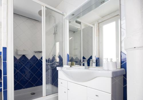 une salle de bain avec un lavabo blanc et une douche dans l'établissement CIA - Bastille, rue de la Roquette, à Paris