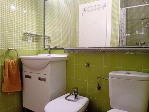 een badkamer met een wastafel, een toilet en een spiegel bij PolaPop Vacation in Santa Pola