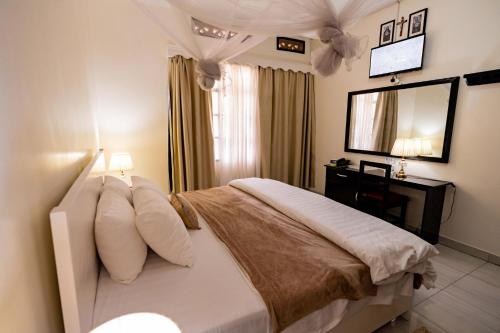 a bedroom with a bed with a mirror and a television at Blue Veil Villa Hotel in Kigali