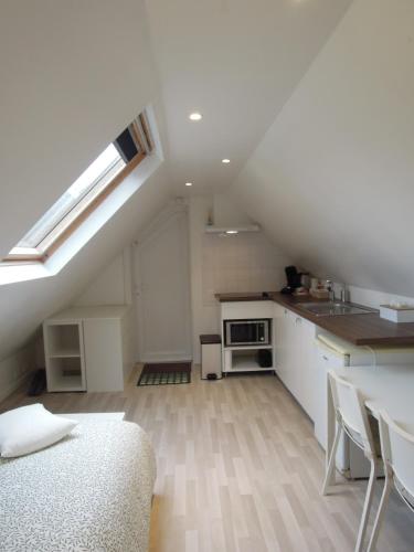 an attic kitchen with a skylight and a table and chairs at Sous un toit perché in Grez-Doiceau