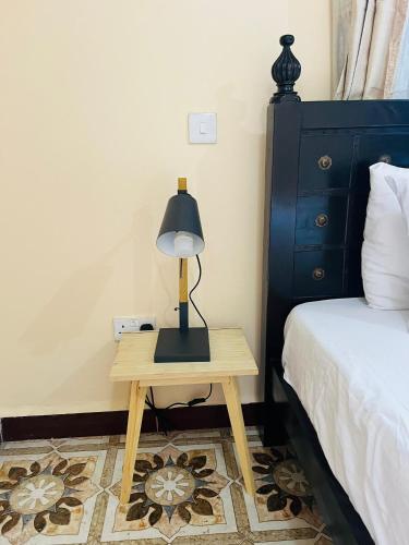 a lamp on a table next to a bed at The Luxe Apartment in Zanzibar City