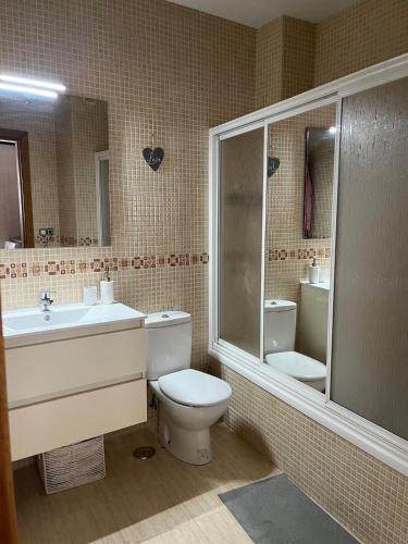 a bathroom with a toilet and a sink and a mirror at Estudio zona residencial in Don Benito