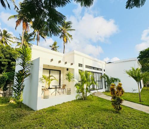 a white house with palm trees and grass at Watamu Ochre Villas in Watamu