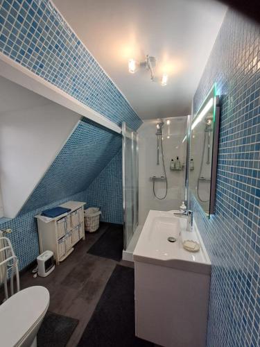 a blue tiled bathroom with a sink and a shower at BERNAY Chambre avec Salon, salle d'eau privative et entrée indépendante in Bernay