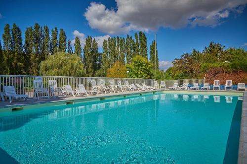 une grande piscine avec des chaises et une clôture dans l'établissement Camping Les Fontaines, à Ivry-la-Bataille