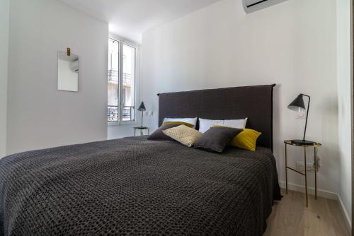 - une chambre avec un lit noir et des oreillers jaunes dans l'établissement Scandinavian Urban 2 - 2BR apartment in center close to Palais des Festivals and the beach, à Cannes