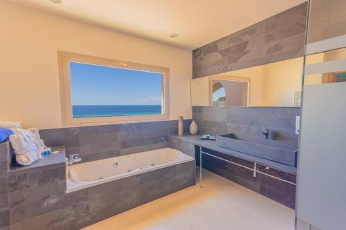 un bagno con vasca, lavandino e finestra di Villa Treya - Star property stunning views a Son Bou