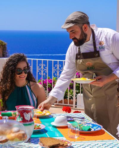 a man and a woman preparing food at a table at Masa Villas in Praiano