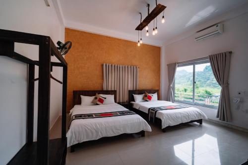 a bedroom with two beds and a window at Ethnic JR in Dồng Văn