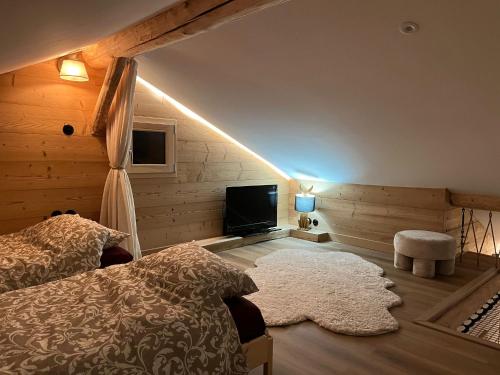 a bedroom with a bed and a flat screen tv at L Authentique Vosgien in Vecoux