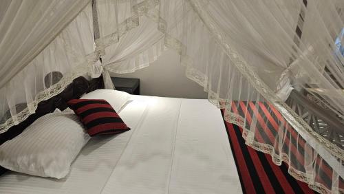 a white canopy bed with a red and black pillow at Ridee Villa in Unawatuna