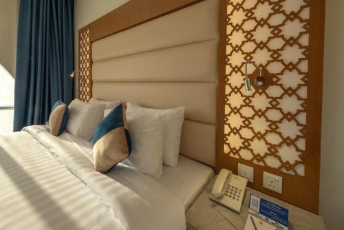 a bed with white pillows and a telephone in a room at Le Beaurivage Hotel in Jeddah