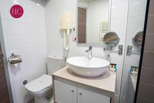 a white bathroom with a sink and a toilet at Central Hotel, Fitness and Spa in Vinica