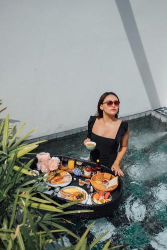 a woman sitting in a pool of water with a tray of food at Sugar Marina Resort-LAGOON-Villas, Naiyang Beach in Nai Yang Beach