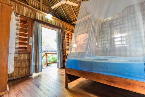 a bedroom with a bed with a mosquito net at Chez Maggie Hotel & Restaurant in Morondava