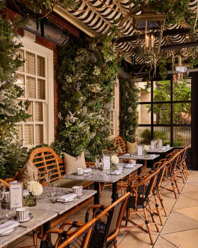 a dining room with tables and chairs and plants at The Bloomsbury Hotel in London