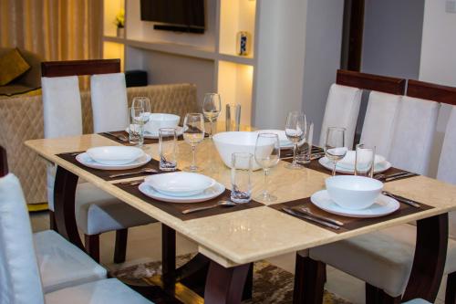 a wooden table with wine glasses and plates on it at Georgia Apartment 1A1 in Mombasa