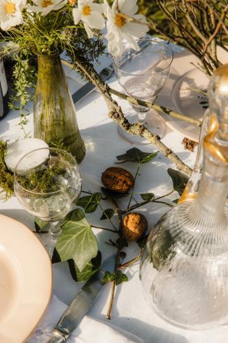 a table with glasses and vases and flowers on it at Repère Sauvage in La Ville-aux-Clercs