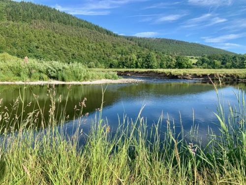 a river in the middle of a field with mountains at Stravaig in Innerleithen