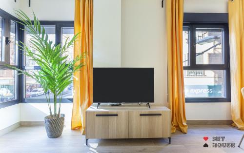 a tv on a cabinet in a room with windows at Antonio Lopez en Madrid in Madrid
