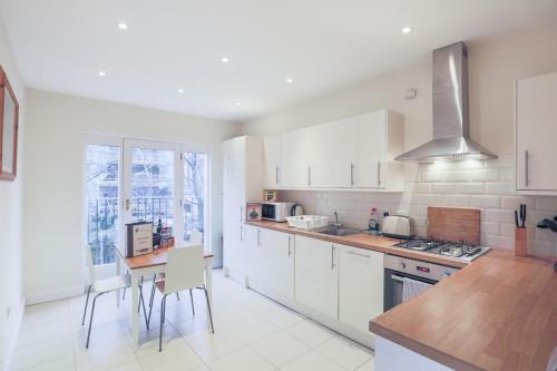 a kitchen with white cabinets and a table with chairs at Notting Hill 2 Bed Flat - 5 min to Portobello Road in London