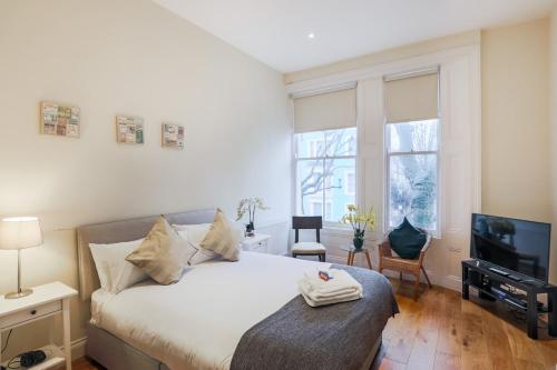 a bedroom with a large bed and a television at Notting Hill 2 Bed Flat - 5 min to Portobello Road in London