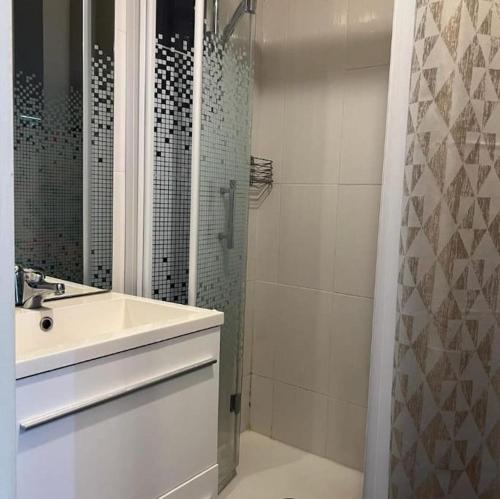 une salle de bain blanche avec un lavabo et une douche dans l'établissement Studio vue port et mer Cap d'Agde île des Pêcheurs, au Cap d'Agde