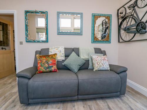 a couch in a living room with pictures on the wall at Elderflower Lodge in Grange Over Sands