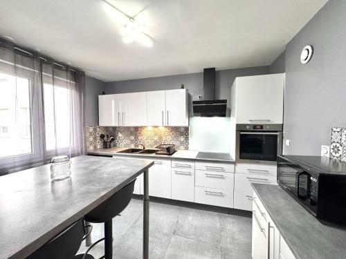 une cuisine avec des placards blancs et un grand comptoir dans l'établissement Le Citybreak BeauT4 Moderne Terrasse-Centre-Ville Parking gratuit, à Saint-Priest