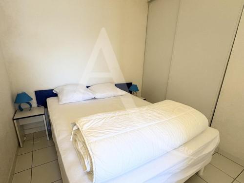 - une chambre avec 2 lits avec un triangle sur le mur dans l'établissement 1 CHAMBRE, DERNIER ETAGE AVEC ASC, CLIM, RES AVEC PISCINE, à Sète