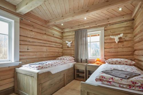 a log cabin bedroom with two beds and two windows at Obidza 438 chata w górach in Obidza