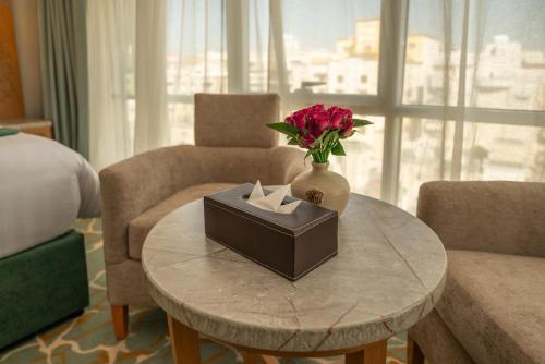 a table with a vase of flowers and a box of tissues at Le Beaurivage Hotel in Jeddah