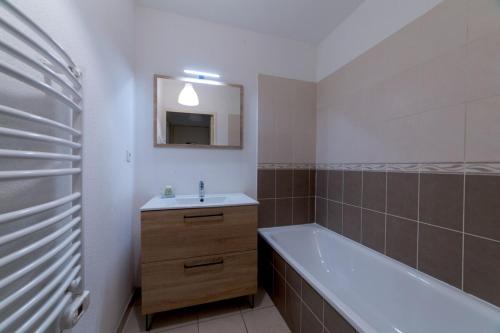 une salle de bain avec un lavabo, une baignoire et un miroir dans l'établissement Charmant appartement - Villeurbanne Centre, à Villeurbanne