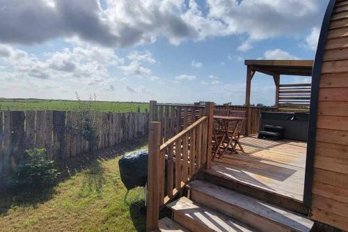 a wooden deck with a table and a grill at The Galloway Steading - The Herons Nest, secure garden and with Hot Tub and Fire Pit in Glenluce