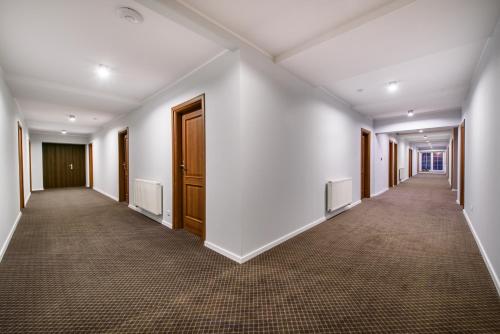an empty corridor with white walls and wooden doors at Hotel Nowy Dwór in Trzebnica