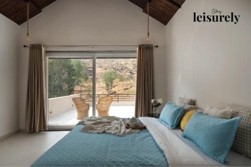 a bedroom with a bed and a large window at Stay Leisurely Terra 2BHK & Timber 2BHK, Igatpuri in Balayaduri