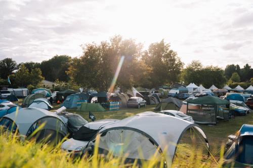 un grand groupe de tentes dans un champ arboré dans l'établissement Bronze - Camping, au Mans