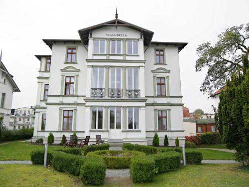 ein großes weißes Haus mit einem Garten davor in der Unterkunft Villa Bella - direkt an der Promenade in Ahlbeck