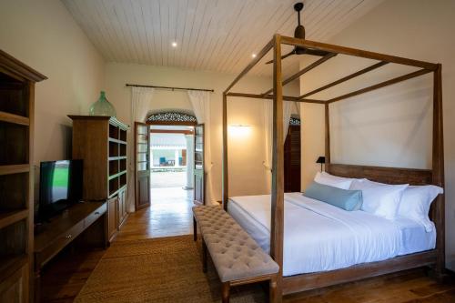a bedroom with a canopy bed and a television at Clodagh Manor House by Seven Angels in Matale